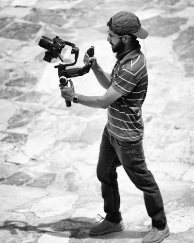 Filmmaker operating camera rig in bright sunlight.